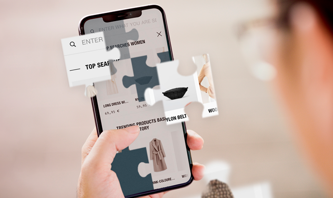 IMAGE DESCRIPTION: An anonymous hand is holding a smartphone, the screen shows a fashion ecommerce site split into pieces of a puzzle.